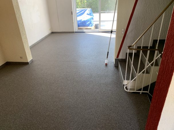Grauer Steinteppich im Flur mit angrenzender Innentreppe und Terrassentür.