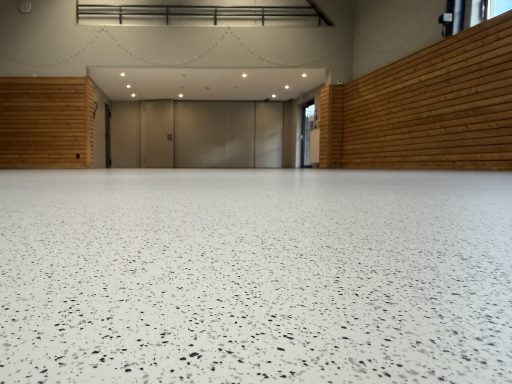Die neue Oberfläche im Detail Nahaufnahme der hellen, mit Farbchips gestalteten Bodenoberfläche.